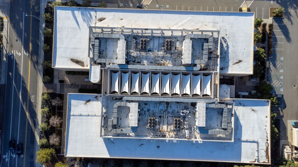 Aerial top down view of a flat roof of a commercial building with industrial HVAC units. Ponding dirty water spots.