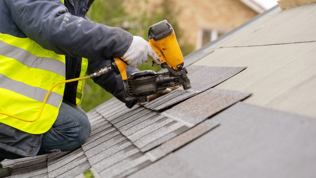 roofer installing new asphalt shingles on roof
