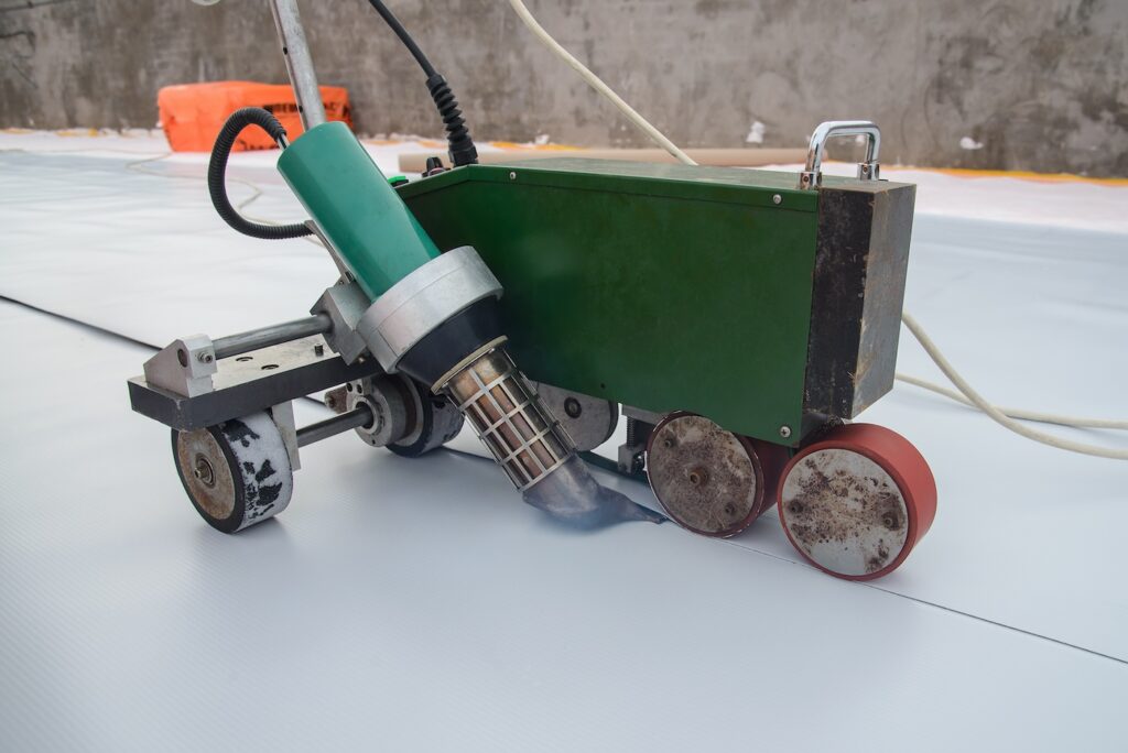 Waterproofing and insulation at construction site, roof sealing process of synthetic membrane with Automatic plastic welder. New protection technology