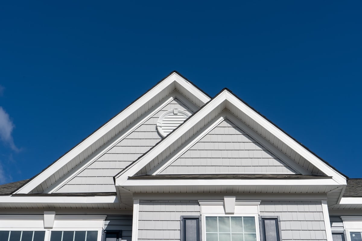 Double gable with grey horizontal vinyl siding and round attic ventilation on a new single family home