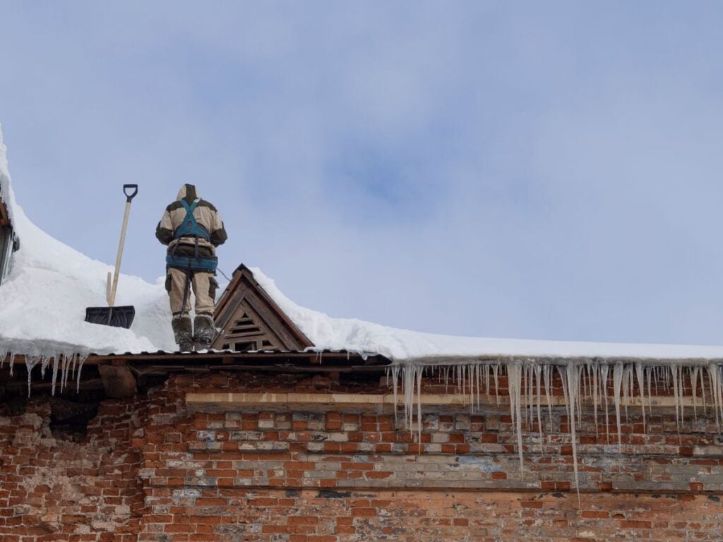 ice dam removal wadsworth oh worker on top of roof shovel cleaning