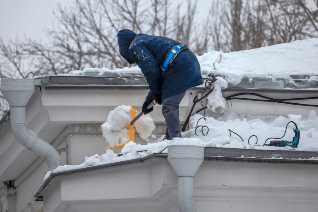 ice dam removal strongsville oh worker using shovel to remove snow on roof big house