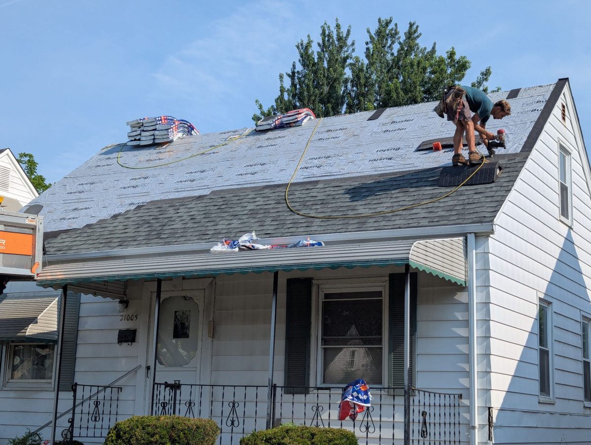 residential roof repair workers on top of roof replacing shingles