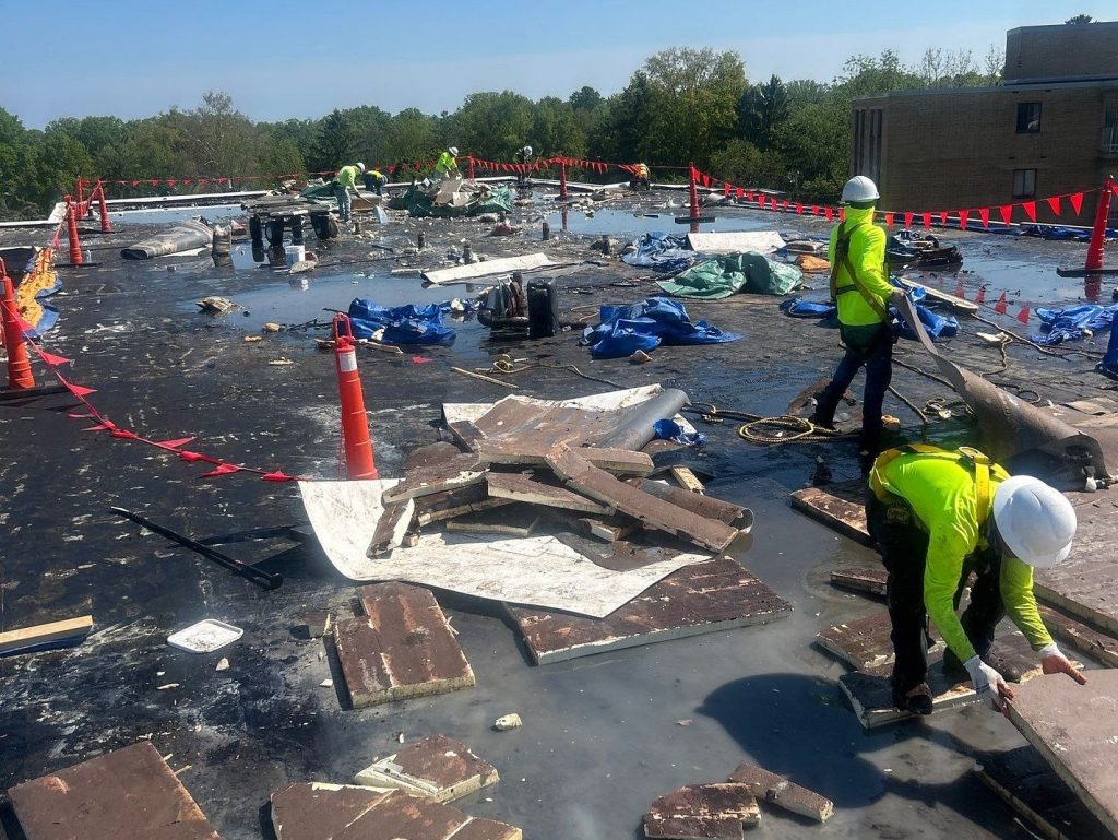 commercial roof replacement workers using green shirt fixing roof