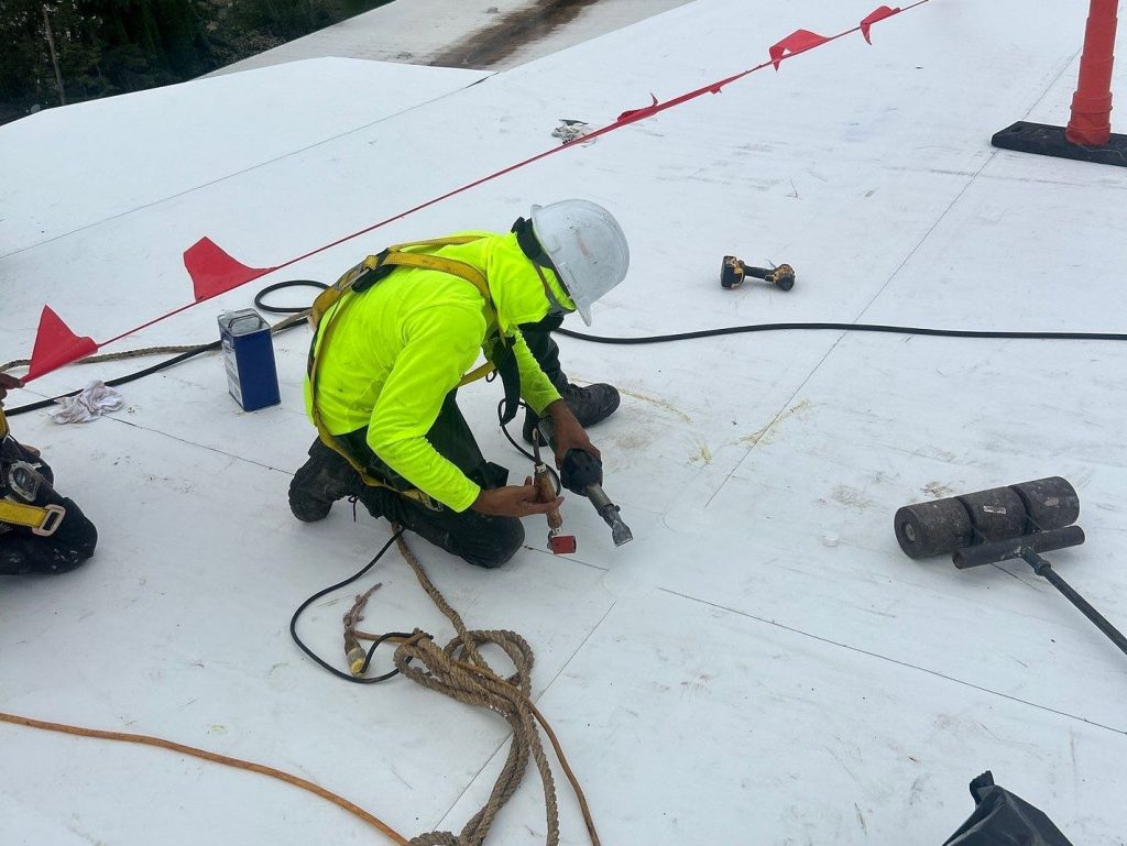 commercial roof replacement worker on TPO roof